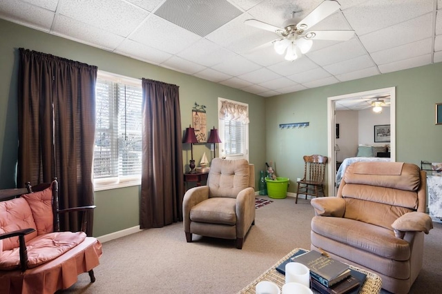 carpeted living area featuring baseboards, a paneled ceiling, and a ceiling fan