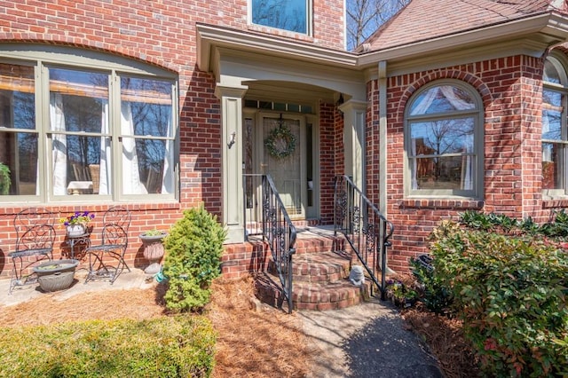 property entrance featuring brick siding and roof with shingles