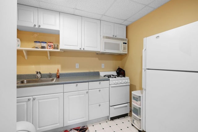 kitchen with a sink, a paneled ceiling, white appliances, and white cabinets