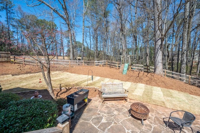 view of patio featuring fence, a fire pit, and playground community