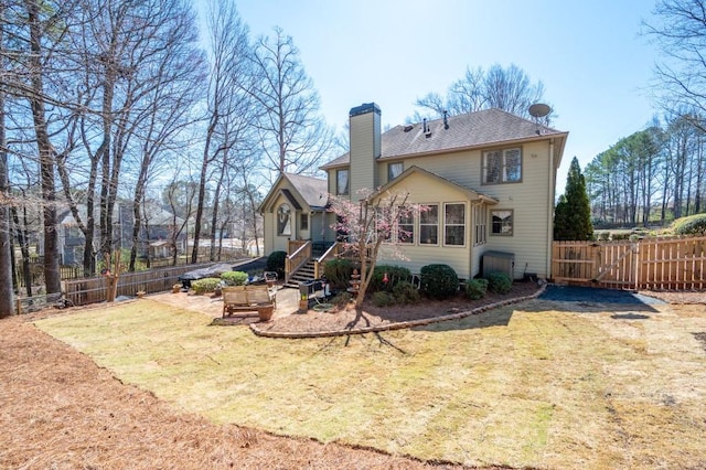 back of property featuring a gate, a chimney, a yard, and fence