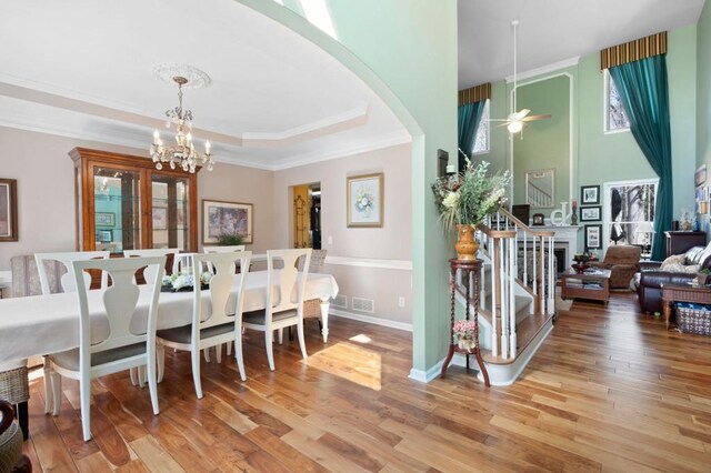 dining space with baseboards, a tray ceiling, ornamental molding, stairs, and light wood-style floors