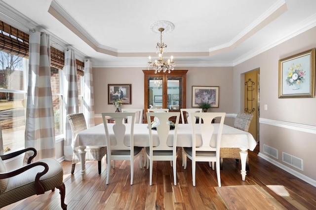 dining space featuring a wealth of natural light, a raised ceiling, and an inviting chandelier