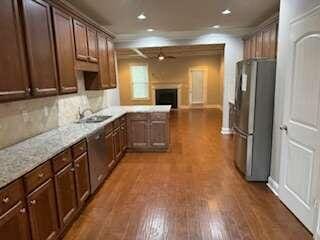 kitchen with stainless steel refrigerator, tasteful backsplash, light stone countertops, dark hardwood / wood-style floors, and crown molding