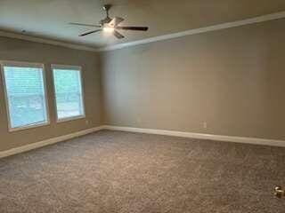 carpeted empty room featuring ornamental molding and ceiling fan