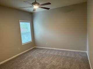 carpeted spare room with ceiling fan