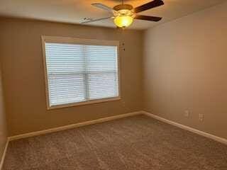 carpeted spare room featuring ceiling fan