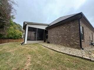 rear view of house featuring a lawn and a sunroom