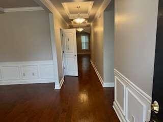 hall with dark wood-type flooring and ornamental molding