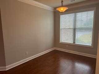 spare room with plenty of natural light, crown molding, and dark hardwood / wood-style flooring