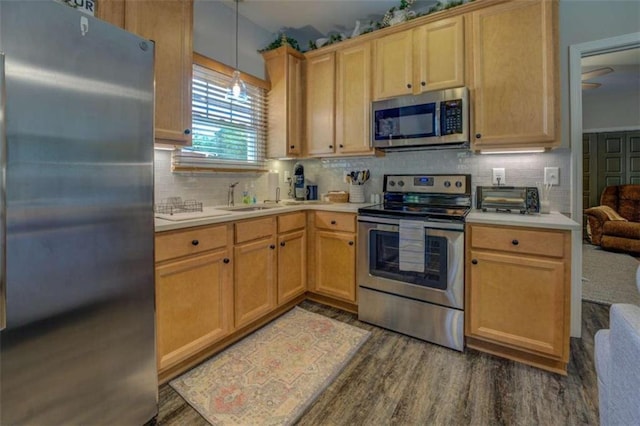 kitchen with sink, decorative light fixtures, dark hardwood / wood-style flooring, backsplash, and stainless steel appliances