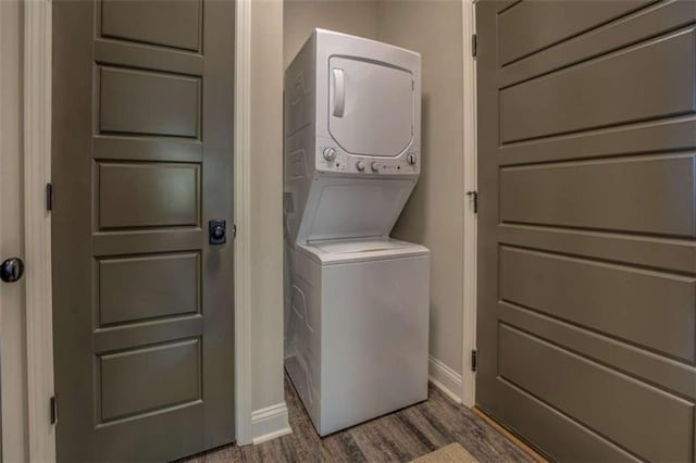 laundry area with dark hardwood / wood-style flooring and stacked washer and dryer