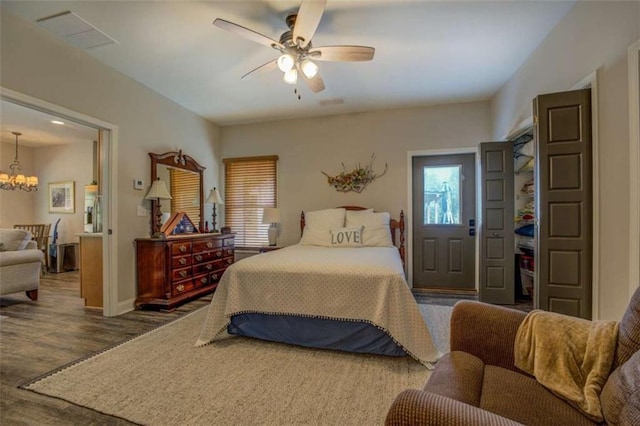 bedroom featuring ceiling fan with notable chandelier and dark hardwood / wood-style flooring