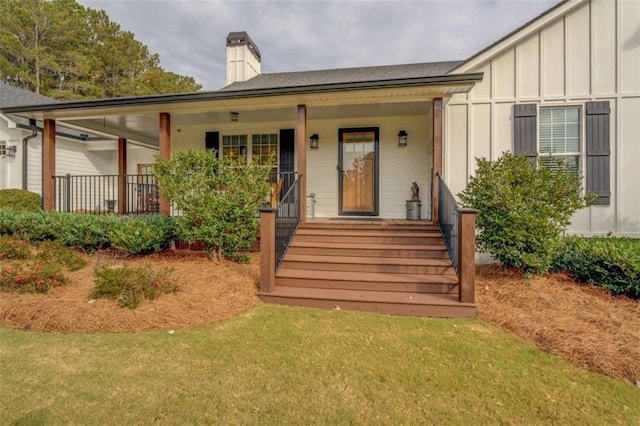 entrance to property with covered porch and a lawn