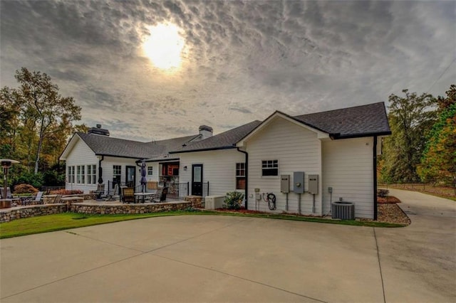 back house at dusk with a patio area and central AC unit