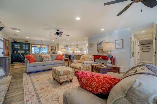 living room with ceiling fan with notable chandelier, light hardwood / wood-style flooring, and crown molding