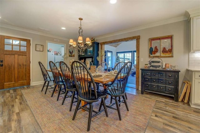 dining area featuring light hardwood / wood-style flooring, ornamental molding, and a notable chandelier