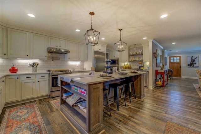 kitchen featuring hanging light fixtures, dark hardwood / wood-style flooring, appliances with stainless steel finishes, white cabinets, and a kitchen island