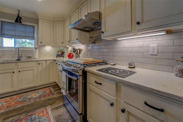 kitchen featuring light stone countertops, tasteful backsplash, sink, dark wood-type flooring, and stainless steel gas range oven