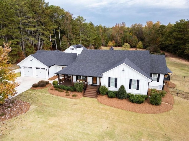 modern inspired farmhouse with a garage, covered porch, and a front yard