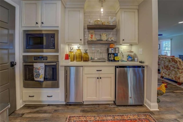 kitchen with decorative backsplash, white cabinets, appliances with stainless steel finishes, and dark hardwood / wood-style floors