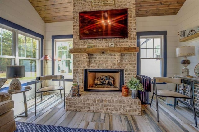 living area with wood-type flooring, wooden walls, and vaulted ceiling