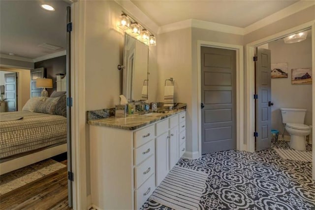 bathroom with toilet, vanity, and crown molding