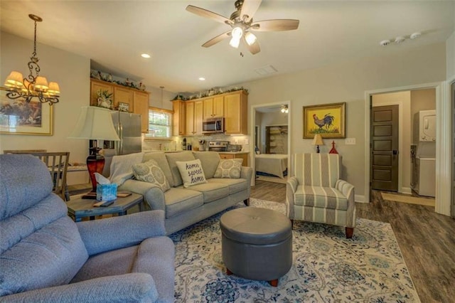 living room with ceiling fan with notable chandelier and dark hardwood / wood-style flooring