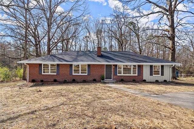 ranch-style home featuring board and batten siding, brick siding, and a chimney