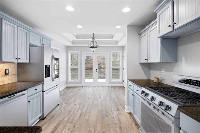 kitchen with tasteful backsplash, recessed lighting, stainless steel appliances, light wood-style floors, and a raised ceiling