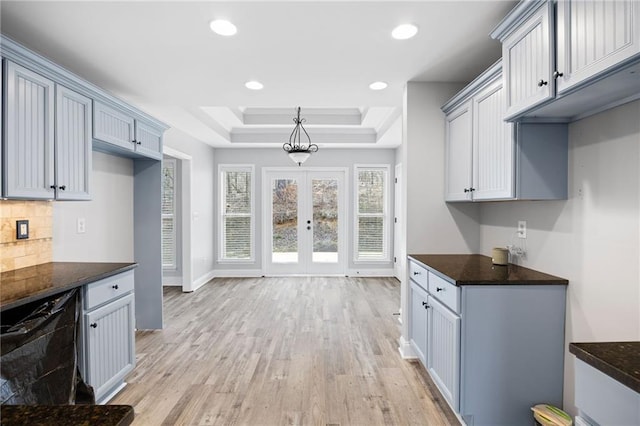 kitchen featuring baseboards, light wood-style flooring, recessed lighting, a raised ceiling, and tasteful backsplash