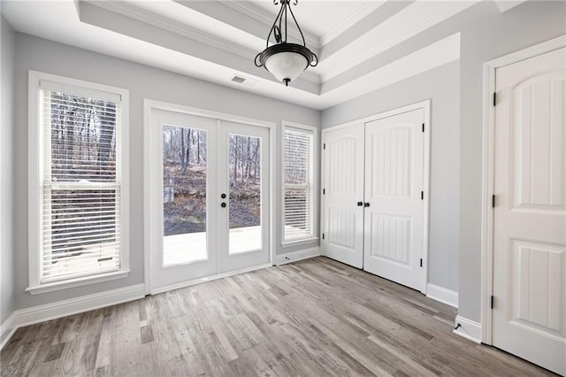 interior space featuring visible vents, a raised ceiling, wood finished floors, and access to exterior