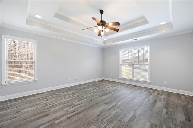 spare room featuring crown molding, baseboards, wood finished floors, a raised ceiling, and a ceiling fan