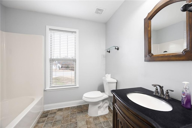 bathroom featuring visible vents, toilet, stone finish floor, baseboards, and vanity