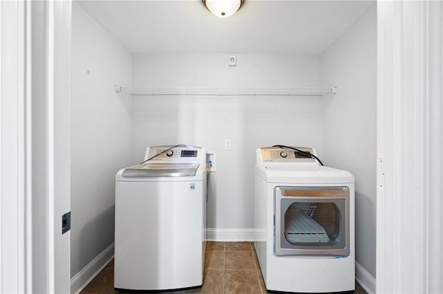 laundry room featuring baseboards, dark tile patterned flooring, laundry area, and washer and clothes dryer