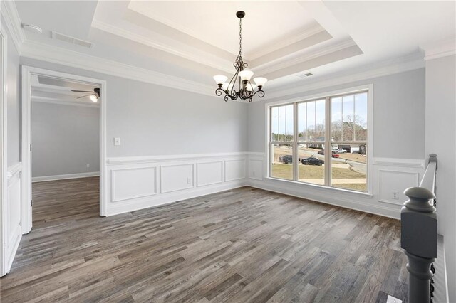 unfurnished room featuring a tray ceiling, visible vents, wood finished floors, and an inviting chandelier