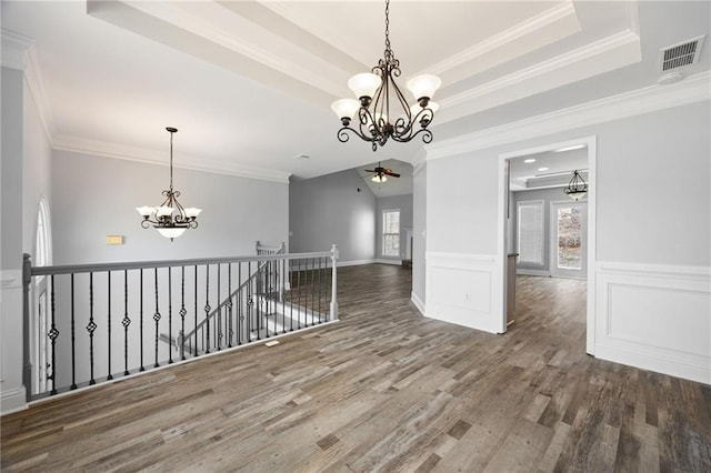 unfurnished room featuring visible vents, crown molding, a tray ceiling, wainscoting, and wood finished floors