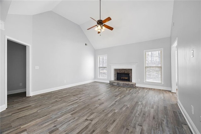 unfurnished living room featuring high vaulted ceiling, a healthy amount of sunlight, wood finished floors, and a fireplace