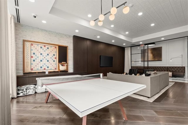 recreation room featuring dark hardwood / wood-style floors and a raised ceiling