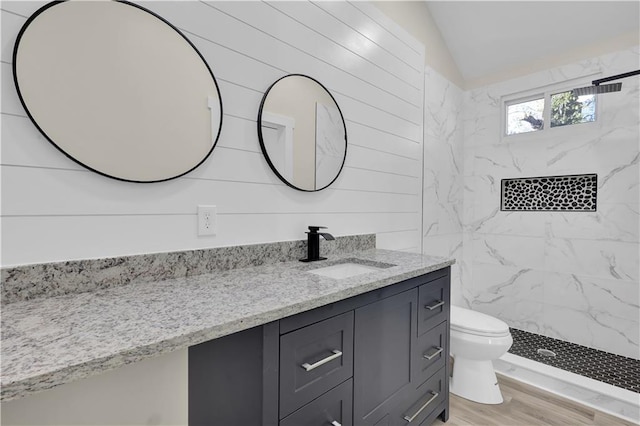 bathroom featuring vanity, lofted ceiling, hardwood / wood-style flooring, toilet, and a tile shower