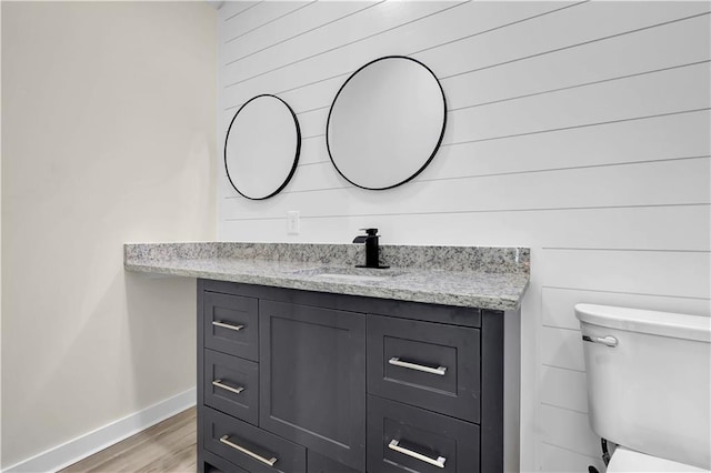 bathroom with wood-type flooring, vanity, and toilet