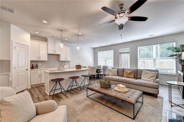 living area with light wood-type flooring, ceiling fan, visible vents, and recessed lighting