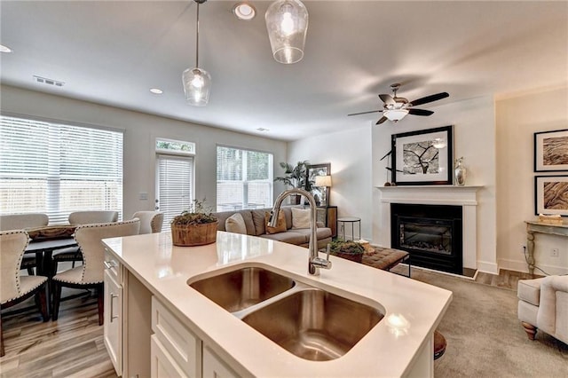 kitchen with visible vents, a glass covered fireplace, open floor plan, hanging light fixtures, and a sink