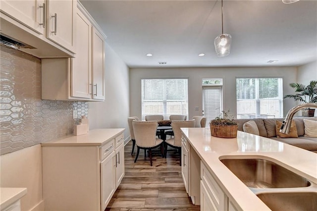 kitchen featuring light countertops, backsplash, open floor plan, a sink, and light wood-type flooring