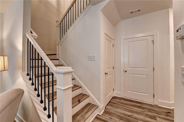 stairs featuring wood finished floors, visible vents, and baseboards