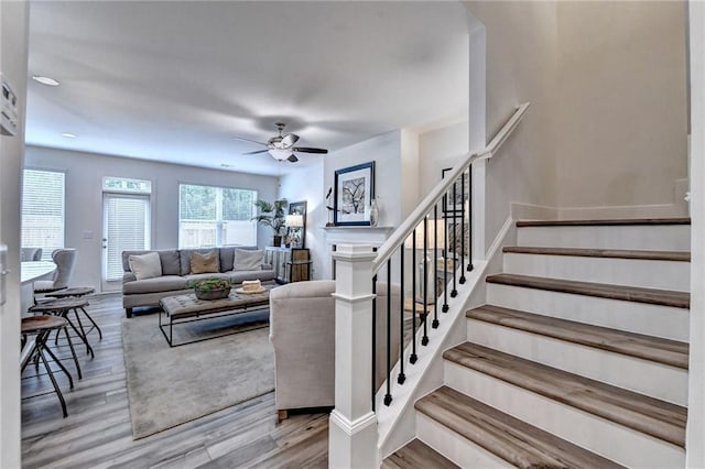 living room featuring stairs, ceiling fan, a fireplace, and wood finished floors