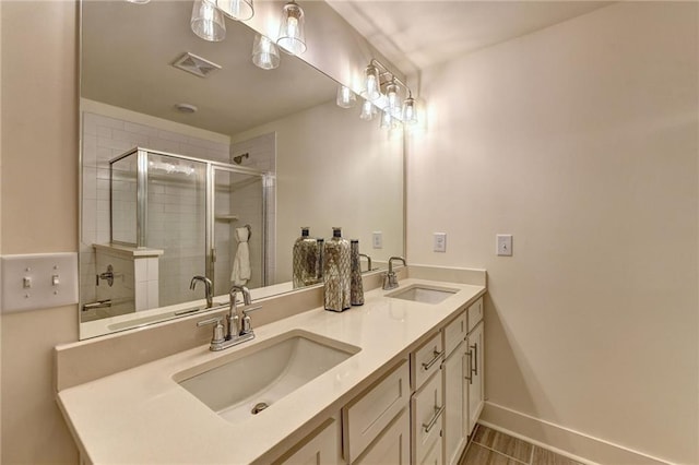 bathroom featuring visible vents, a sink, a shower stall, and double vanity