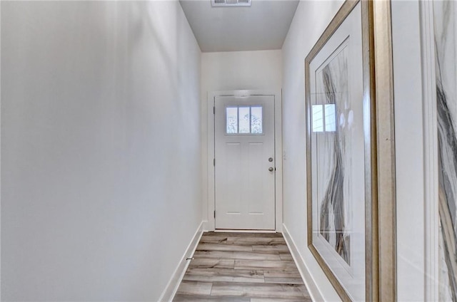 doorway with baseboards, visible vents, and wood finished floors