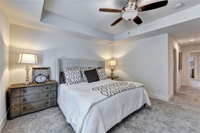 bedroom featuring visible vents, baseboards, a ceiling fan, a tray ceiling, and carpet flooring