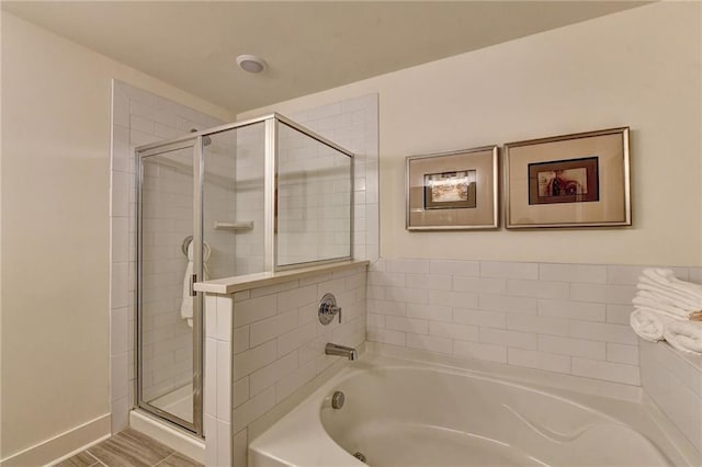 bathroom featuring a stall shower, baseboards, and a bath